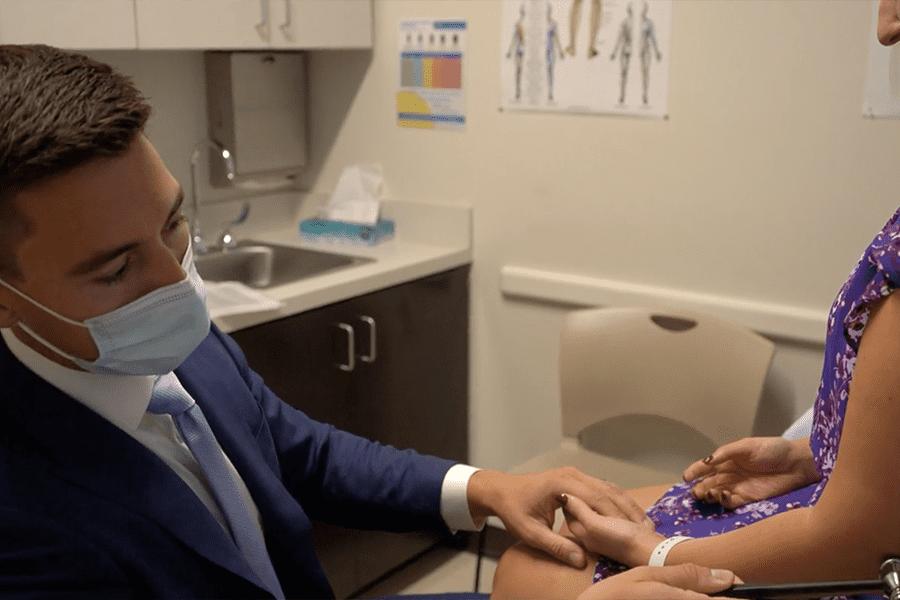 Bryce T. Austell, M.D. examines a female patient's elbow using a stethoscope