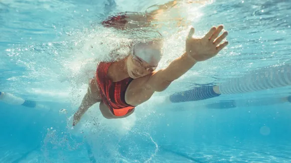 Swimmer in a pool performing a freestyle stroke during training.